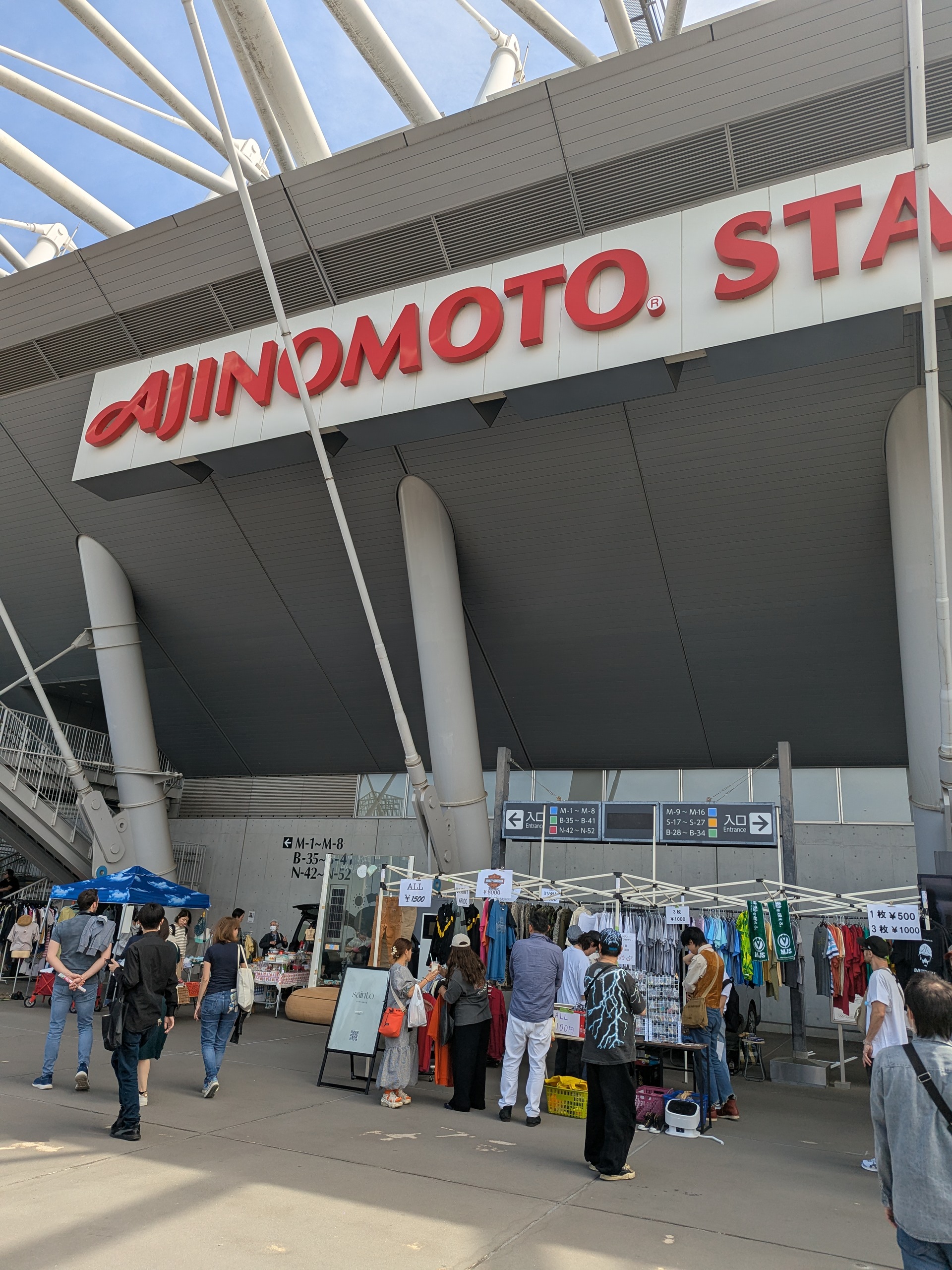 味の素スタジアム コンコースの屋根下に並ぶ古着ショップと来場者の様子